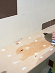 Нанесение клея на фанеру для приклеивания основания столешницы в ванной комнате